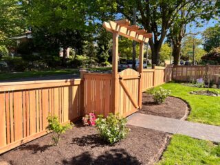 Full panel boundary fence with slats and decorative cedar gate arbor